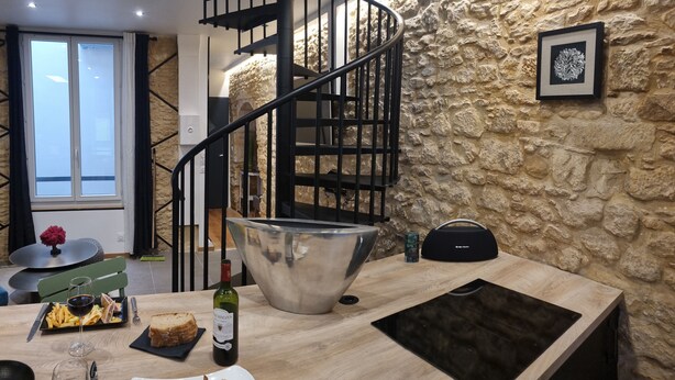 Eine moderne Küche mit Steinwand, einer Wendeltreppe und einem Essbereich mit Tisch für zwei Personen.