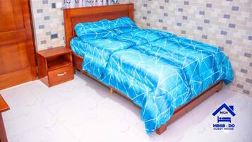 Een slaapkamer met een houten bed, een nachtkastje en een klein ladeblok.