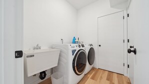 Un lavadero con lavadora, secadora, lavamanos y puerta.