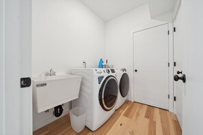 A laundry room with a washing machine, a dryer, a sink, and a door. - Sandy River Group Getaway 2 (Mount Hood Village)
