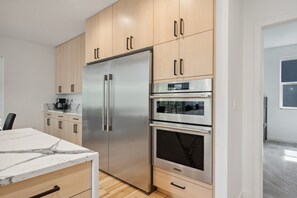 Una cocina moderna con refrigerador de acero inoxidable, horno doble y armarios de madera.