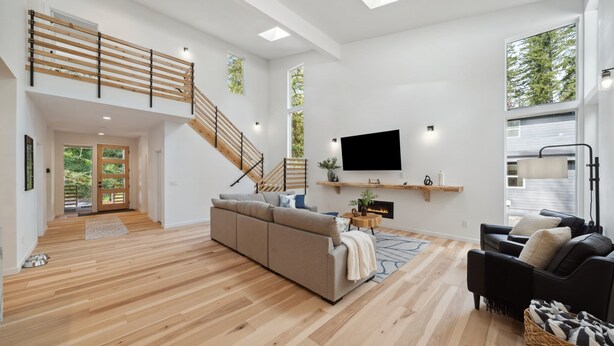 Amplia sala de estar con una escalera de madera, un televisor de pantalla plana grande y una chimenea.