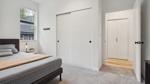 Un dormitorio con una cama, una mesita de noche, una lámpara, una ventana y una puerta.