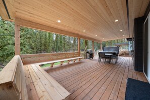 A wooden deck with a built-in barbecue grill and seating area.