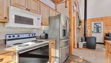 A kitchen with wooden cabinets, a stainless steel refrigerator, a microwave, and a stove.