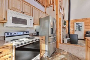Una cocina con armarios de madera, un refrigerador de acero inoxidable, un microondas y una estufa.