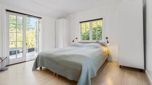 A bedroom with a large bed, a window with a view of greenery, and a balcony with outdoor furniture. - 2 bedroom awesome home in Hornbæk (Hornbæk)