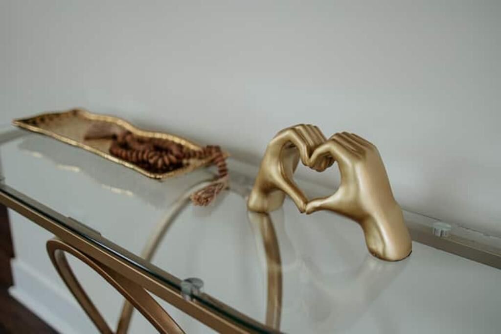 A glass table with a gold heart-shaped object and a brown, leaf-like object on it.