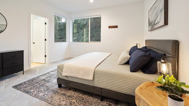 A modern bedroom with a bed, bedside table, and a window. - Sandy River Group Getaway (Mount Hood Village)
