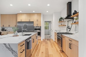 A modern kitchen with wooden cabinets, stainless steel appliances, and a marble countertop.