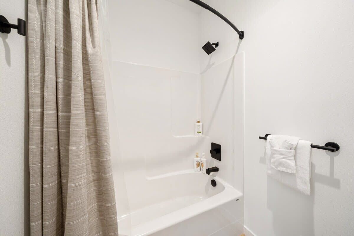 Une salle de bain avec une baignoire, un porte-serviettes et un rideau de douche.