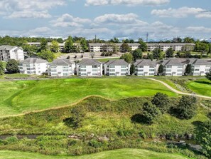 A residential complex with multiple apartment buildings, a well-maintained lawn, and a small stream. - Little House on the 12th Hole - Luxury Golf Condo (Branson)