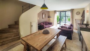 Un'ampia zona giorno con un tavolo da pranzo in legno, una scala e un'ampia finestra che offre vista sull'esterno.