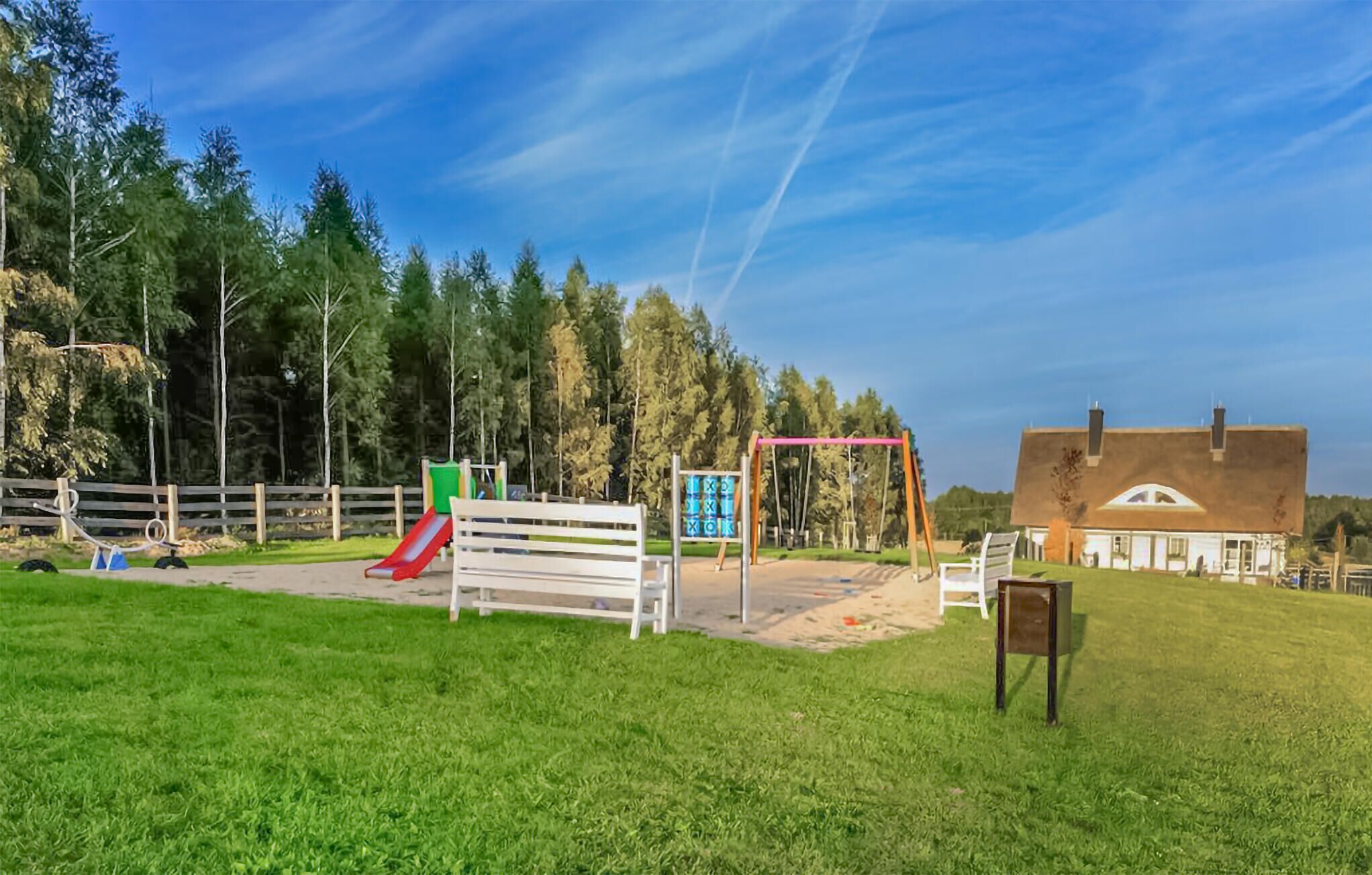 Un parque infantil con tobogán, columpios y un banco.