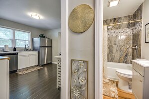 Cocina moderna con refrigerador, lavavajillas y ventana con persianas.