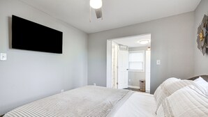 Une chambre avec deux lits, un téléviseur à écran plat fixé au mur et une porte donnant sur une autre pièce.