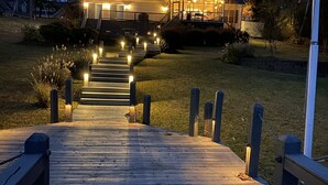 Una terraza de madera que conduce a una casa con porche cubierto y zona de estar al aire libre.