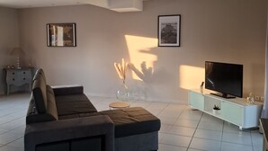 A modern living room with a sofa, TV, and decorative items.