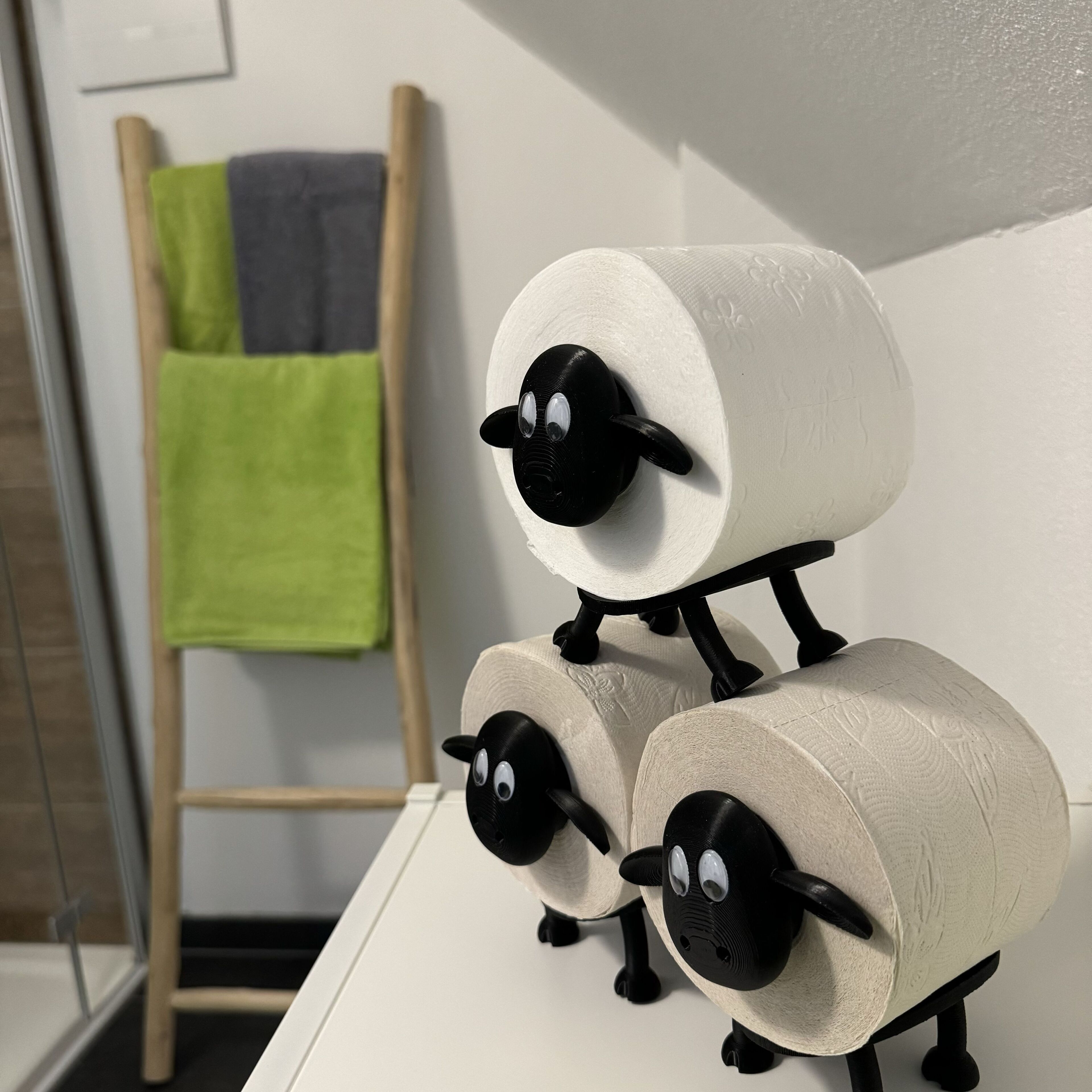 A bathroom with a white sink, a wooden towel rack with a green towel, and a white wall.