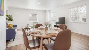 Un espace repas moderne avec une table ronde prévue pour quatre personnes, entourée de chaises marron.