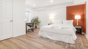 Une chambre à coucher avec un lit, des tables de chevet, un bureau et une chaise.
