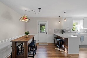 Eine moderne Küche mit Holztisch, Barhocker und Pendelleuchten.