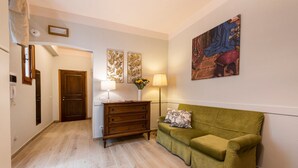 A hallway with a wooden dresser, a green sofa, and a painting on the wall. - Apartments Florence - Ariento Giuditta 2 bdr (Firenze)