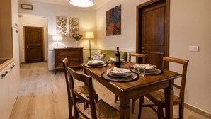 A dining area with a wooden table set for four, a lamp, and a painting on the wall. - Apartments Florence - Ariento Giuditta 2 bdr (Firenze)