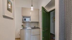 Une cuisine de taille réduite équipée d’un four à micro-ondes, d’un évier et d’un luminaire suspendu.