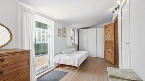 A bedroom with a bed, wooden dresser, and a door leading to another room. - Nice home in Jægerspris with kitchen (Jægerspris)