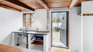 Cocina moderna con techo de madera, un fregadero y ventana con vistas a un jardín.