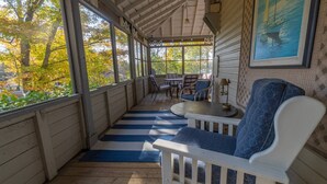 A covered porch with a blue and white striped rug, white wooden furniture, and a painting on the wall. - Large Three Bedroom Retreat Family Friendly Cottage (MacTier)