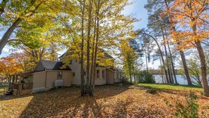 A house with a large yard and a lake in the background. - Large Three Bedroom Retreat Family Friendly Cottage (MacTier)