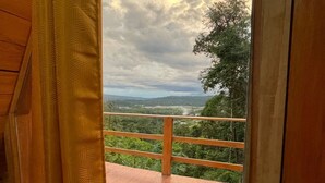 Ein Holzbalkon mit Metallgeländer mit Blick auf eine üppige Landschaft.