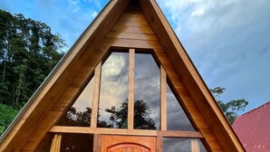 Eine Holzhütte mit einem Giebeldach, großen Fenstern und einer Holztür.