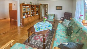 Una sala de estar con una mesa de centro de madera, un sofá floral y un mueble con puertas de vidrio.