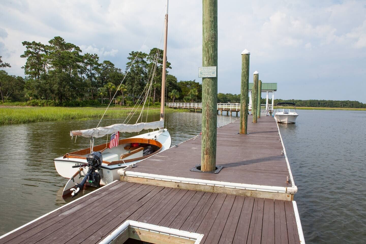 A wooden dock extending into calm water with a small boat docked at the end.