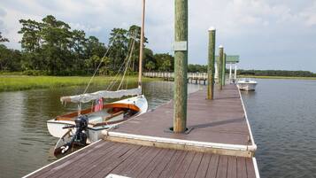 A wooden dock extending into calm water with a small boat docked at the end.