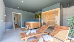Et moderne spaområde med træligge stole, jacuzzi og sauna.