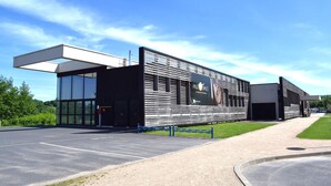 Un edificio moderno con una amplia entrada de vidrio, fachada de metal y un letrero que dice "PALEO SPACE".