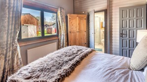 Un dormitorio con una cama grande, un armario de madera y una ventana con cortinas.