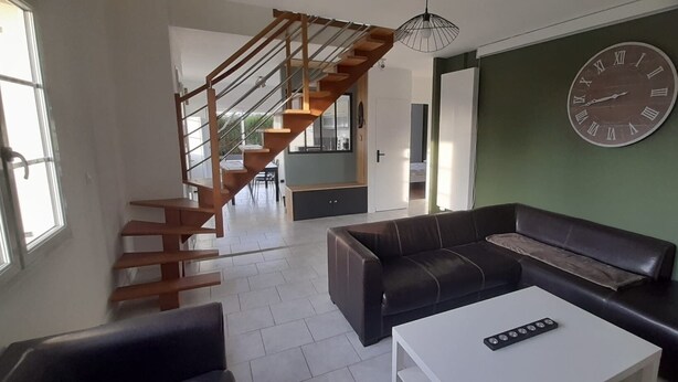 Un salon moderne avec un escalier, une grande horloge et un canapé.