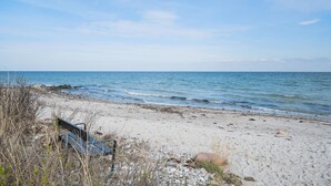 Ein Strand mit einer Bank und felsigem Ufer.