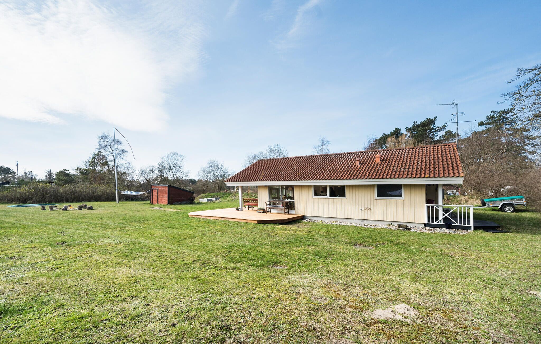 Einbungalow mit Ziegeldach, einer Veranda und einer kleinen Terrasse.