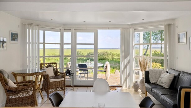 A spacious room with a large sliding glass door leading to an outdoor area, furnished with a table, chairs, and a sofa. - Lovely home in Orø with house sea view (Orø)