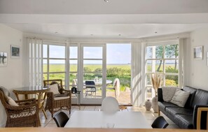 A spacious room with a large sliding glass door leading to an outdoor area, furnished with a table, chairs, and a sofa. - Lovely home in Orø with house sea view (Orø)
