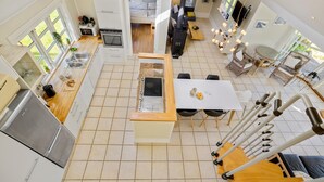 A modern kitchen with a central island, a dining area with a table and chairs, and a living space with a sofa and a TV. - Lovely home in Orø with house sea view (Orø)