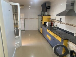 Una cocina compacta con lavadora, microondas y estufa.