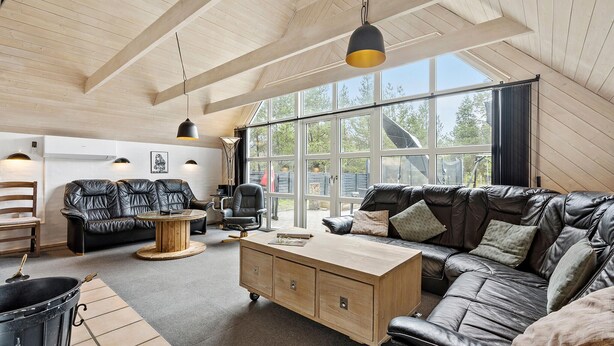 Ein geräumiger Loft mit hohen Decken, großen Fenstern, einem Ledersofa, einem Holztisch und einem kleinen Schreibtisch.