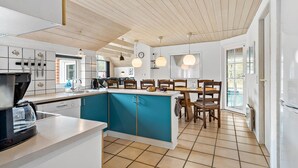 Eine moderne Küche mit einer zentralen Kochinsel, Holzboden und einem Essbereich mit Tisch und Stühlen.